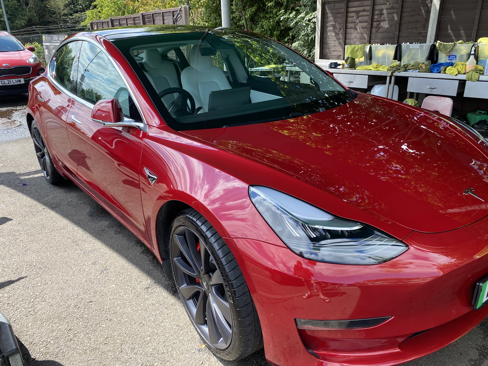 A freshly detailed red Tesla Model 3 outside Elite Valeting